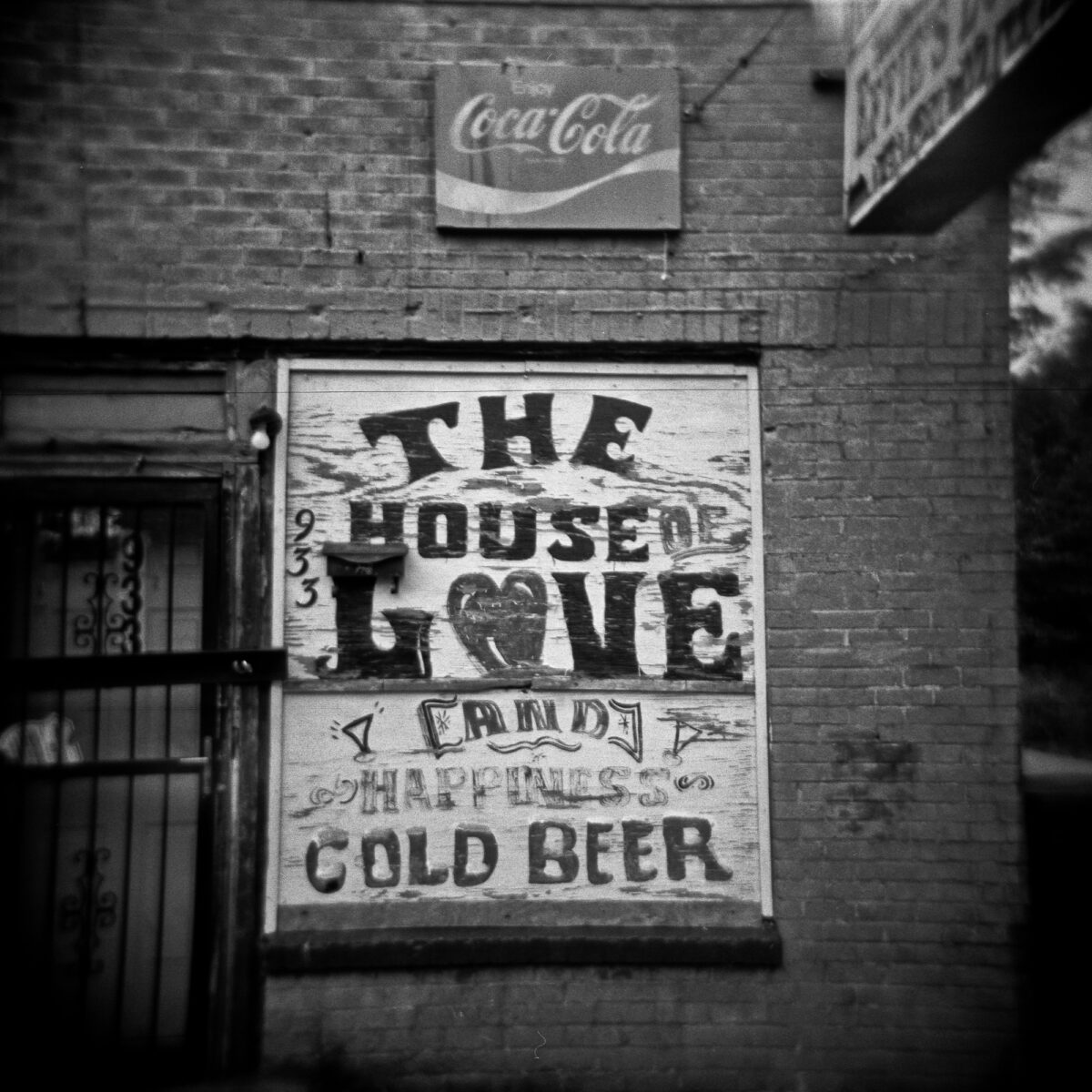 Holga Black and White photo of a sign that reads "The House of Love and Happiness, Cold Beer"